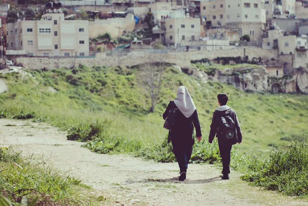 two person walking towards rural area