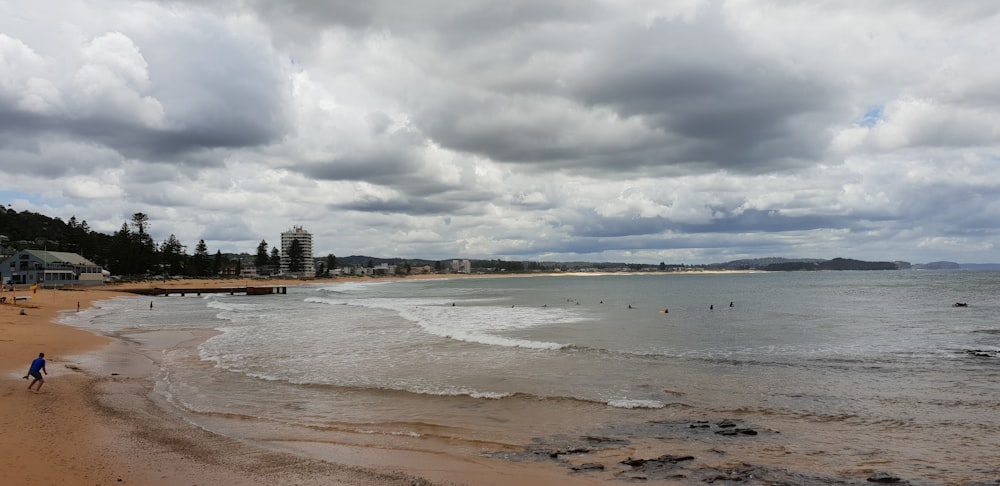 man standing on shore under cloudy sky during daytime