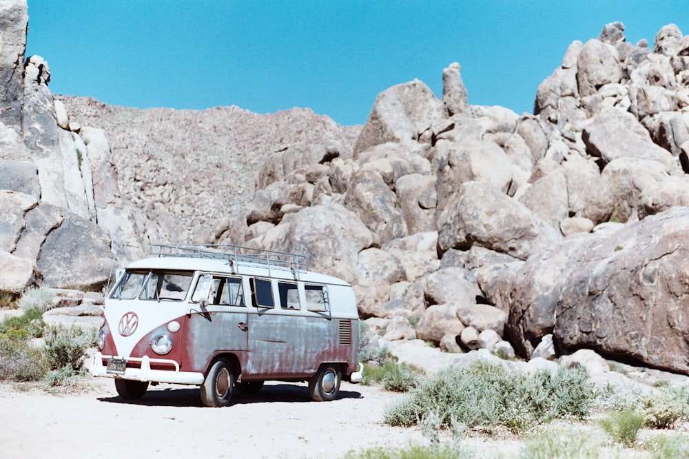 red and white Volkswagen T1 bus parked near rocks during daytime