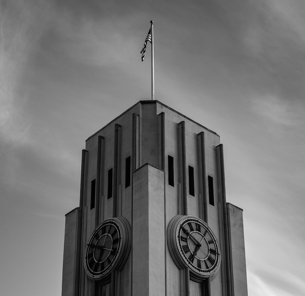 fotografia de baixo ângulo e escala de cinza do relógio da torre com bandeira elevada