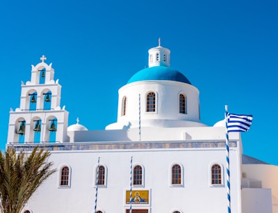 Traditional Greek church with blue dome perched above Lefkes against a clear blue sky.
