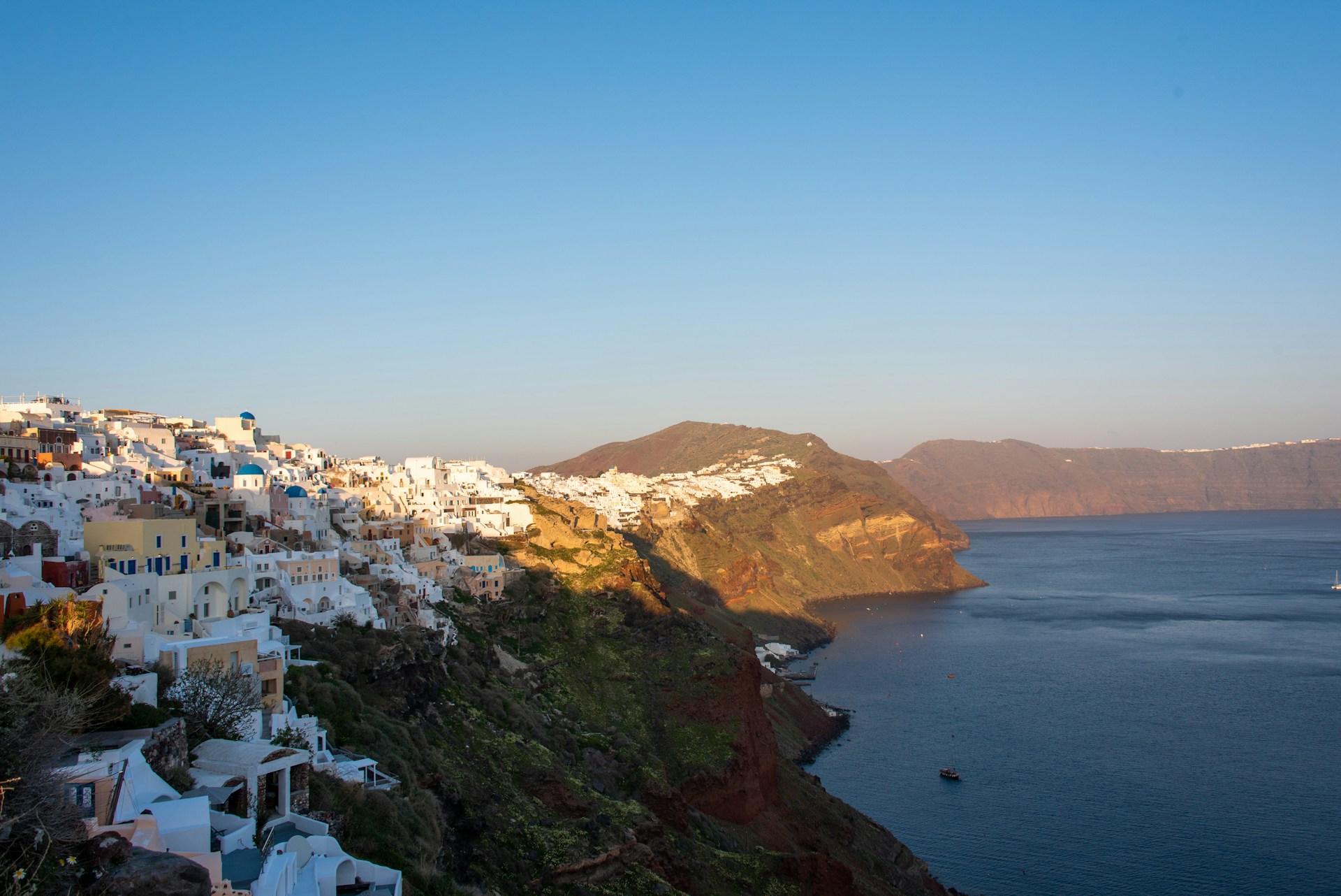 A vibrant sunset over Santorini’s whitewashed buildings and blue domes, inviting travelers to unwind in a picturesque Greek island setting.