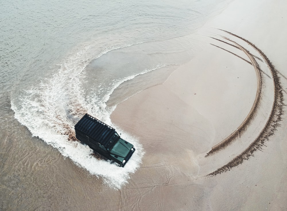 Fuoristrada nero che guida in riva al mare