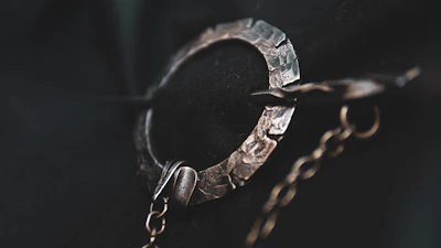Close-up of a handcrafted coffee petal brooch with a pearl centerpiece on a matte cream background.