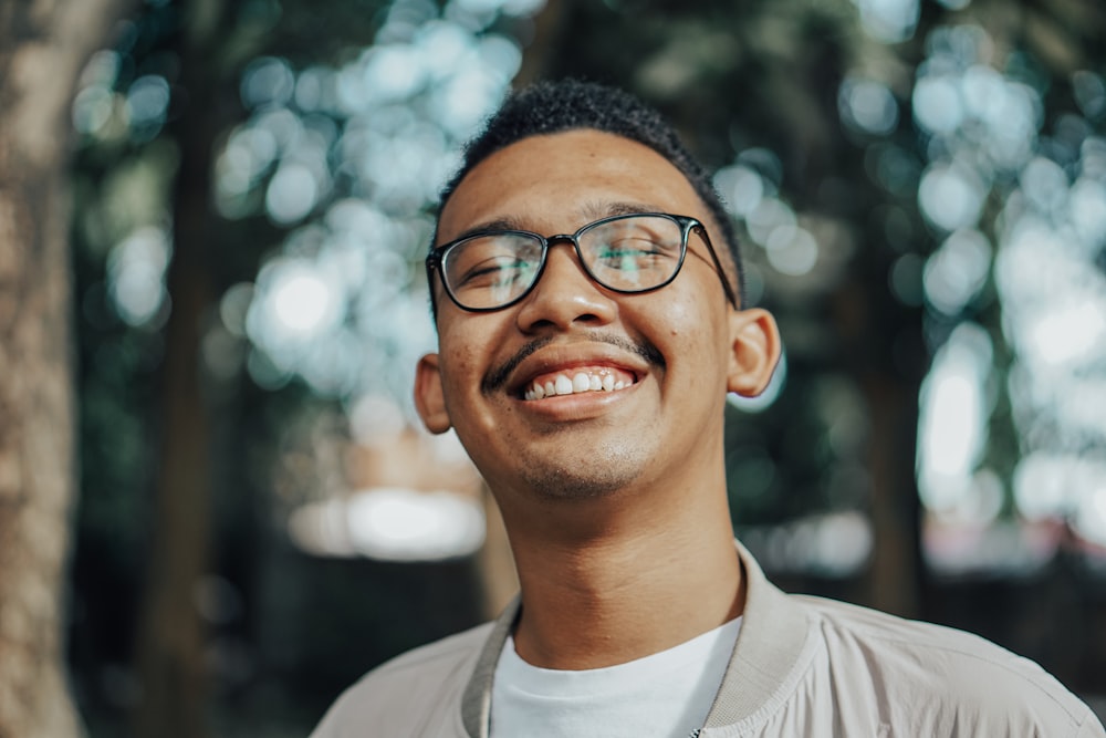 man in beige jacket smiling while wearing eyeglasses