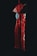 A decorative hanging ornament featuring a red tassel and a jade piece is suspended against a dark background. The ornament's intricate design is illuminated with a red hue, casting dramatic shadows.