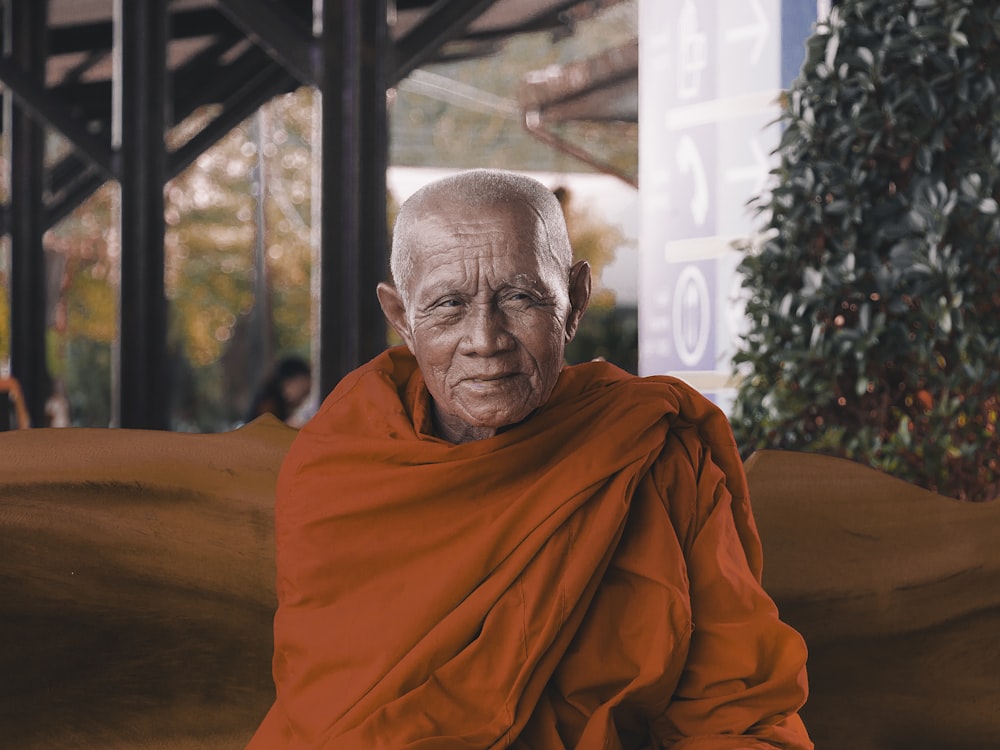 man wearing orange shirt sitting on bench