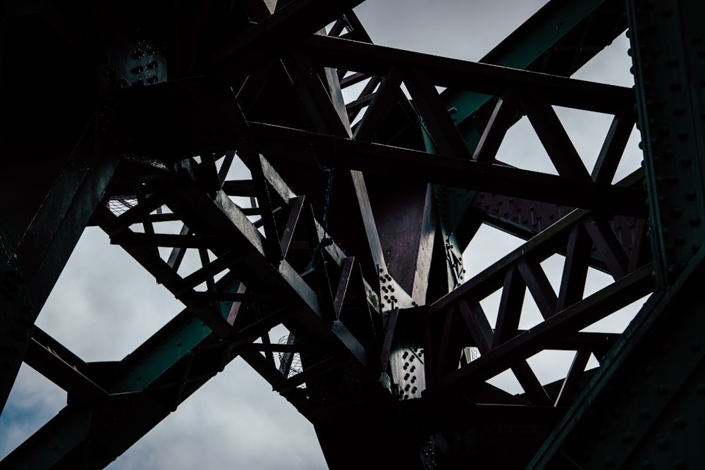 the underside of a metal structure against a cloudy sky