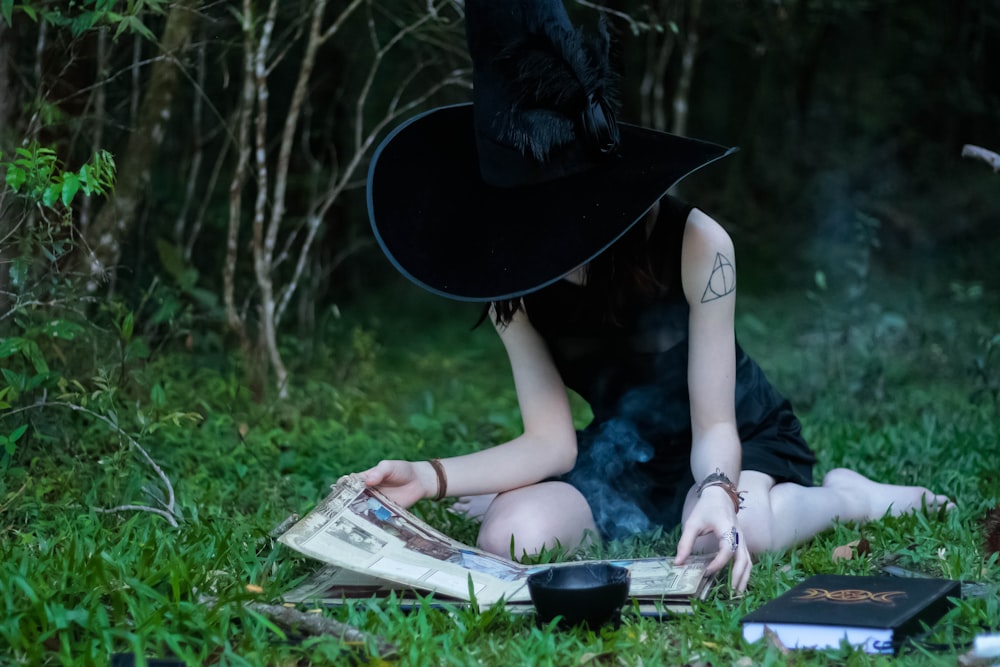 Mujer leyendo un libro mientras está sentada en los pastos verdes del césped
