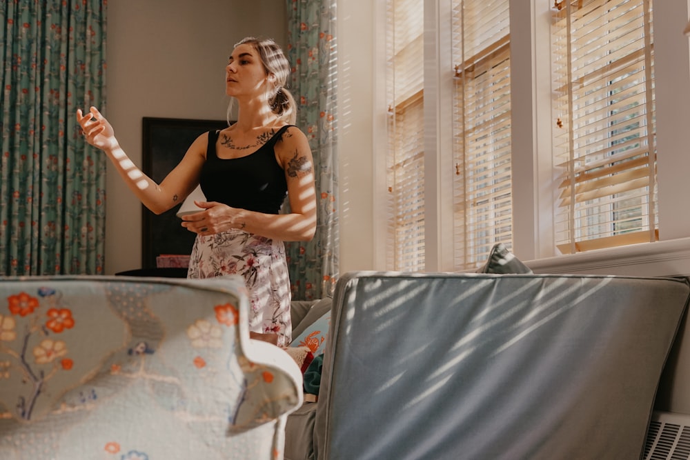 a woman standing in a living room holding a remote