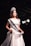 A smiling contestant in a stunning gown on stage at AK Pageant.