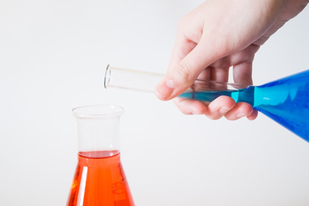 person holding flask pouring to other flask