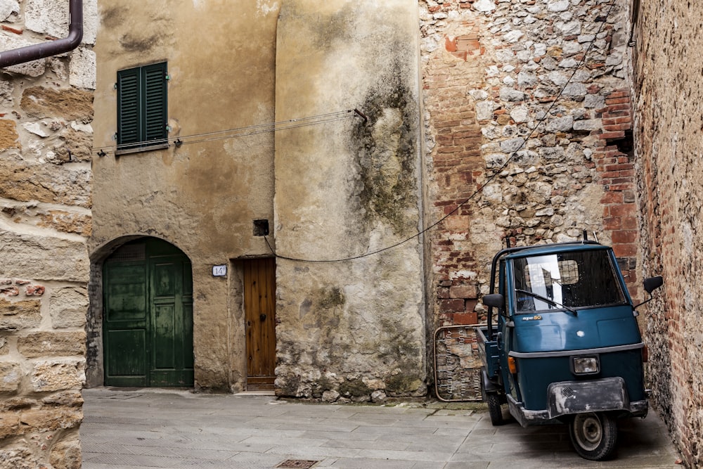 blue and gray auto rickshaw near brown brick wall