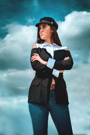 A confident female Air Force leader in uniform, standing tall with arms crossed against a backdrop of a runway at sunset.
