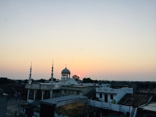 A serene view of Masjid Al Falaq at sunset with villagers gathering for evening prayer.