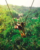 An excited participant soaring on a giant swing with the forested hills in the background.
