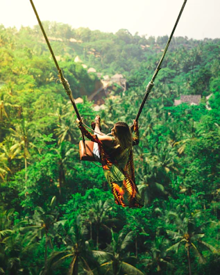 An excited participant soaring on a giant swing with the forested hills in the background.