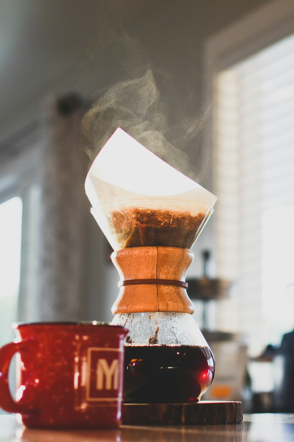 Tasse en céramique rouge à côté d’un vase en verre transparent