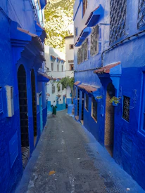 The iconic blue staircases and flower pots of Chefchaouen bathed in soft sunlight.