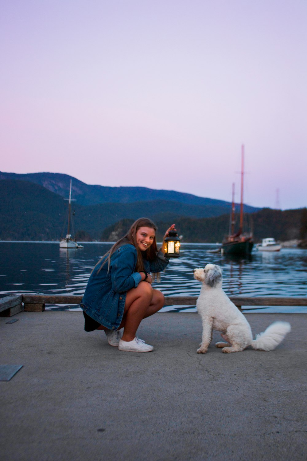 woman holding lantern in front of white dog