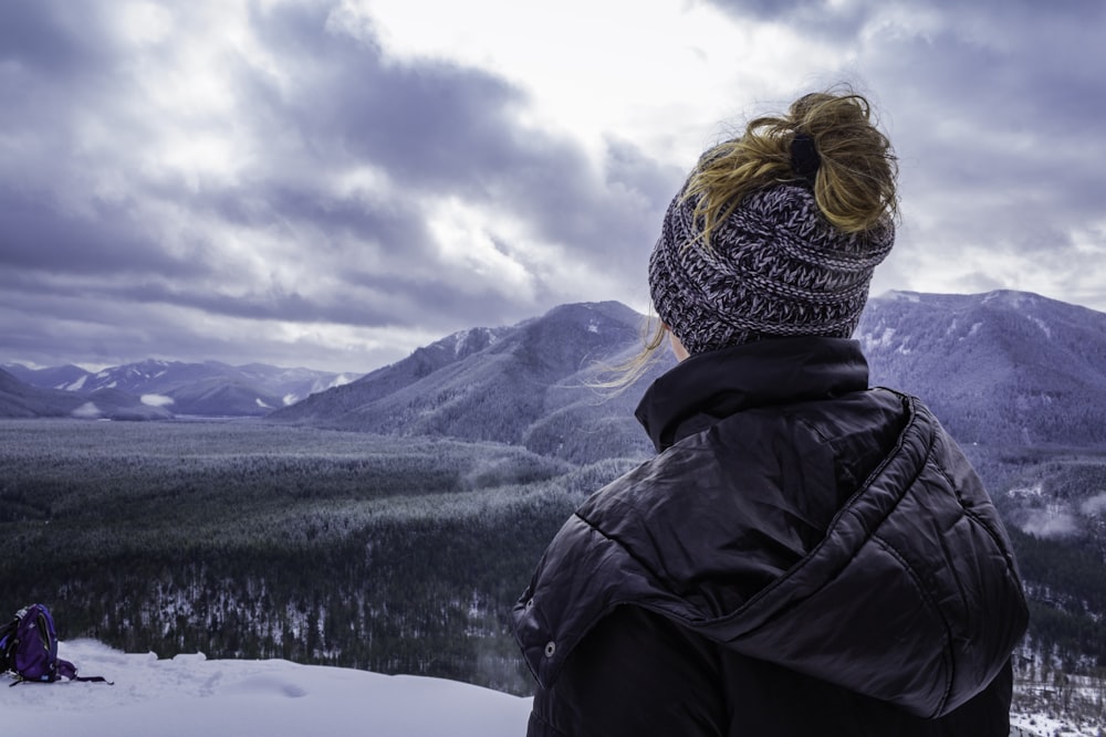 man standing on mountain top overviewing green mountain