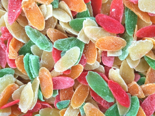 A close-up view of assorted colorful dried fruit slices including shades of green, red, orange, and yellow, which display a sugary coating.