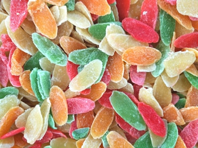 A close-up view of assorted colorful dried fruit slices including shades of green, red, orange, and yellow, which display a sugary coating.