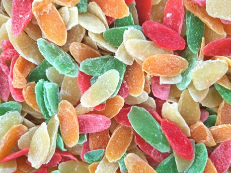 A close-up view of assorted colorful dried fruit slices including shades of green, red, orange, and yellow, which display a sugary coating.