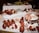 A lavish seafood display features multiple lobsters, large shrimp, a whole fish, lemon slices, and bowls of sauce. The arrangement is on a white tablecloth, suggesting a formal dining or buffet setting.