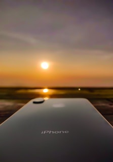 A sleek iPhone resting on a wooden table with a vibrant cityscape blurred in the background.