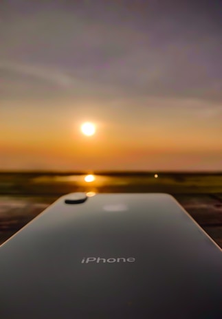A sleek iPhone resting on a wooden table with a vibrant cityscape blurred in the background.