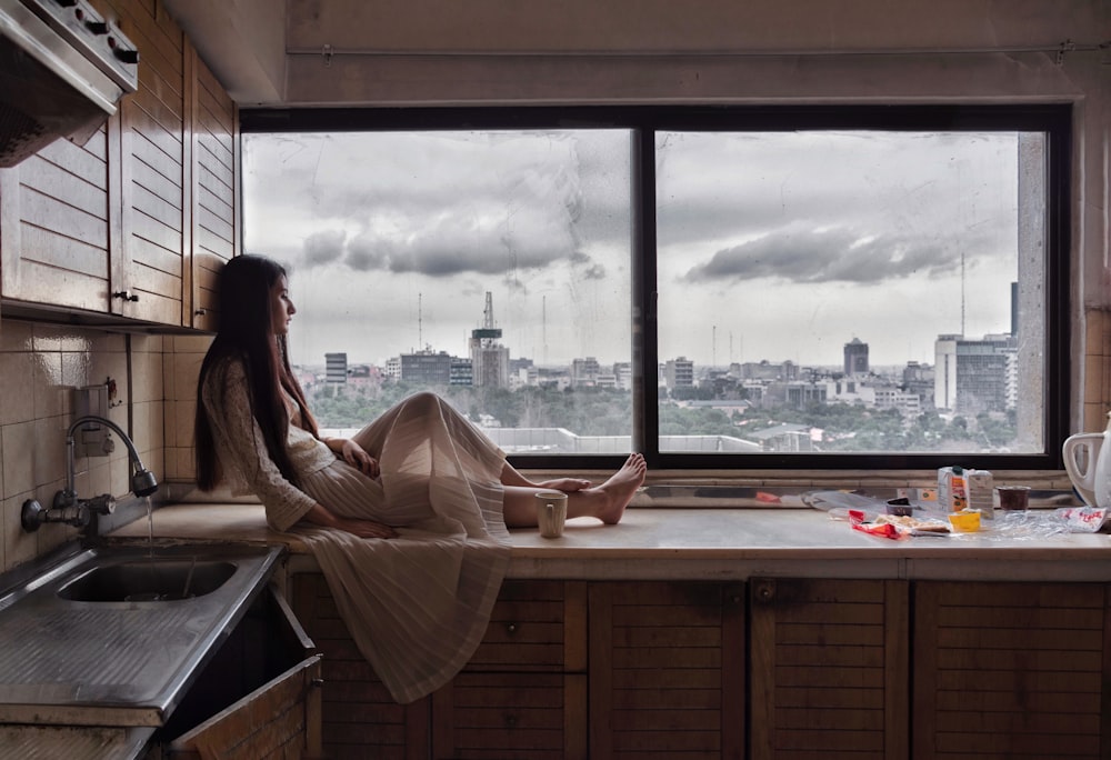 woman sitting near sink and window