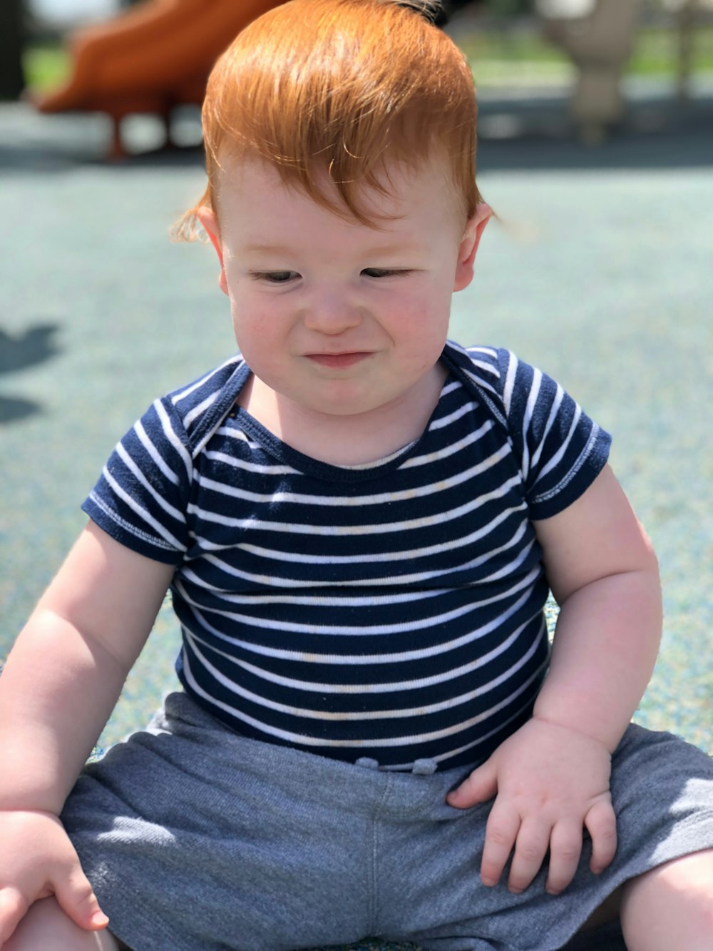 baby wearing black white stripe t-shirt sitting on the ground