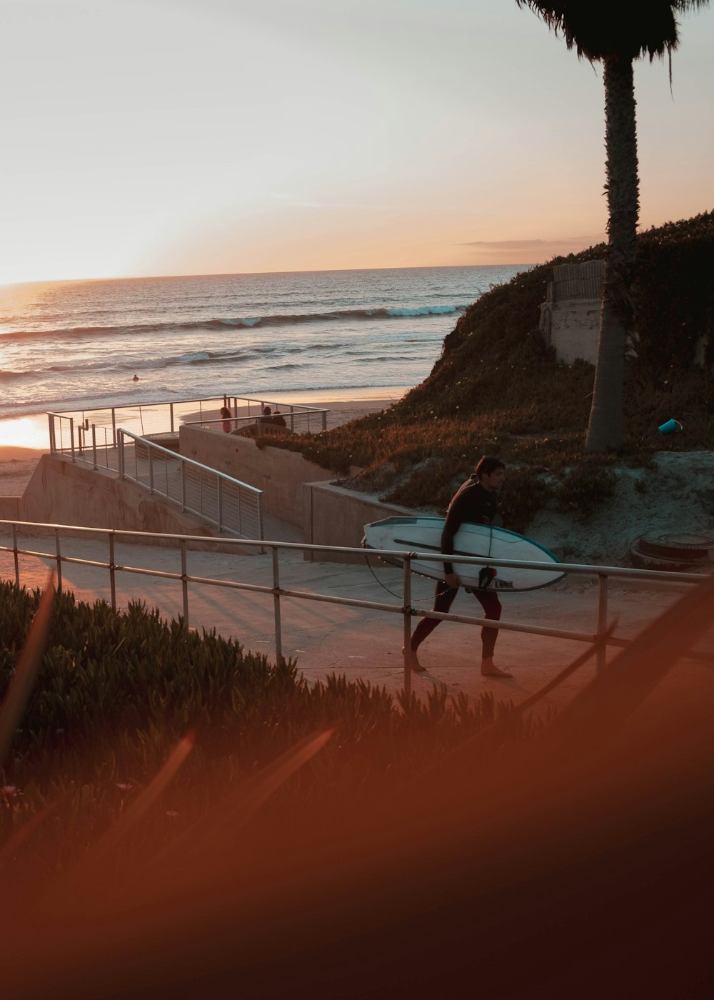 walking man carrying surfboard during golden hour