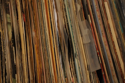 Close-up of colorful vinyl records stacked on a wooden table.