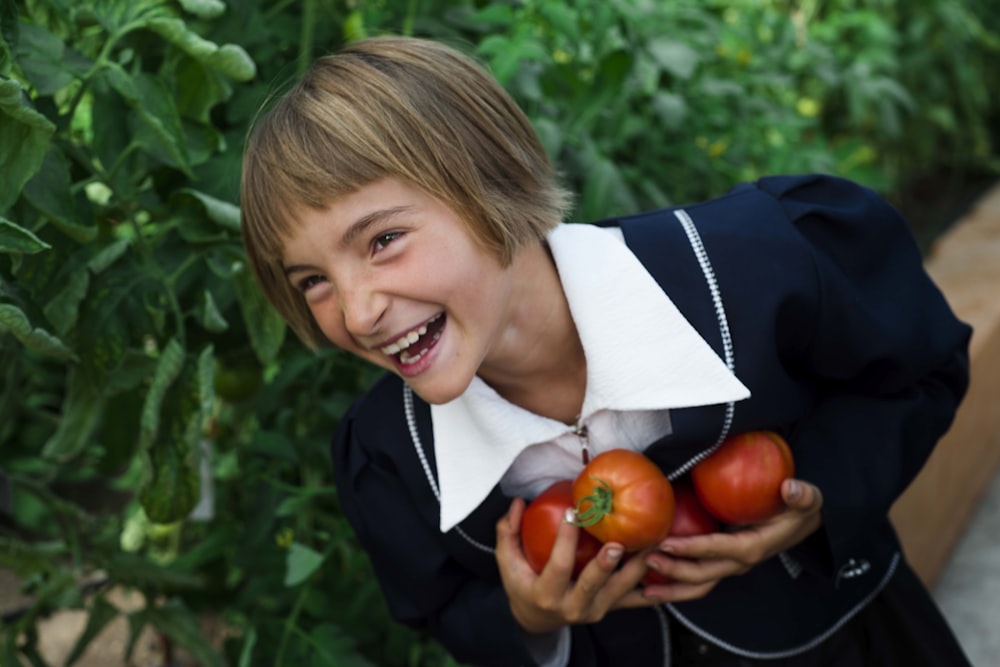 girl in blue dress holding a tomatoes