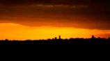 A vibrant night view of Hong Kong skyline glowing with sunset yellow and orange hues.