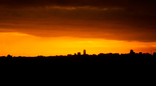 A vibrant night view of Hong Kong skyline glowing with sunset yellow and orange hues.