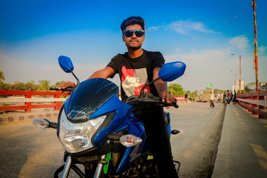 A confident female biker riding along a winding road under a clear blue sky.