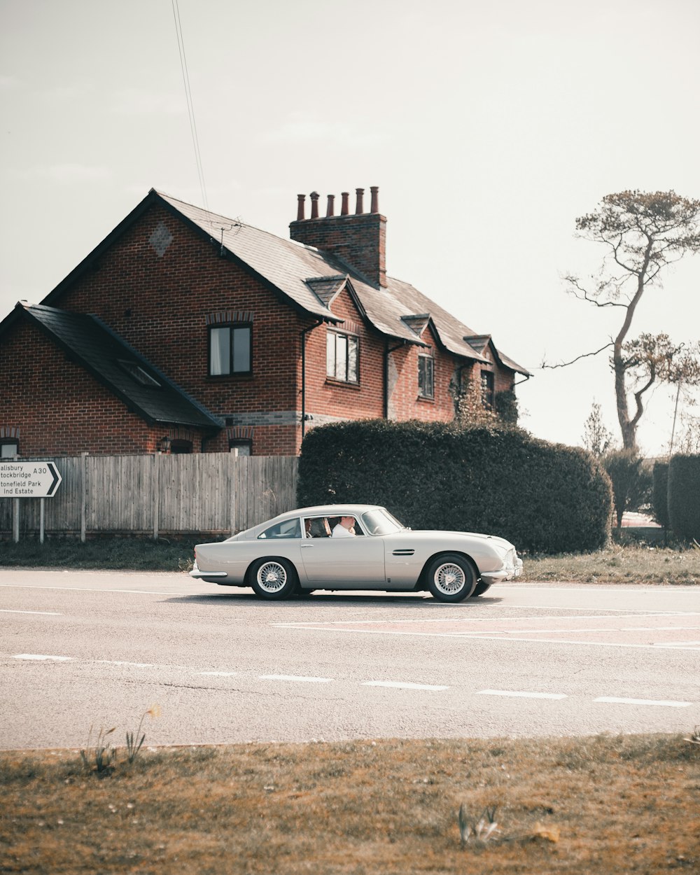 grey coupe parked beside brown wooden house during daytime