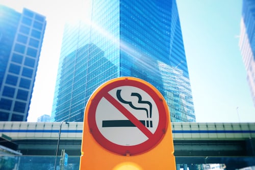 No smoking sign in front of city skyscraper