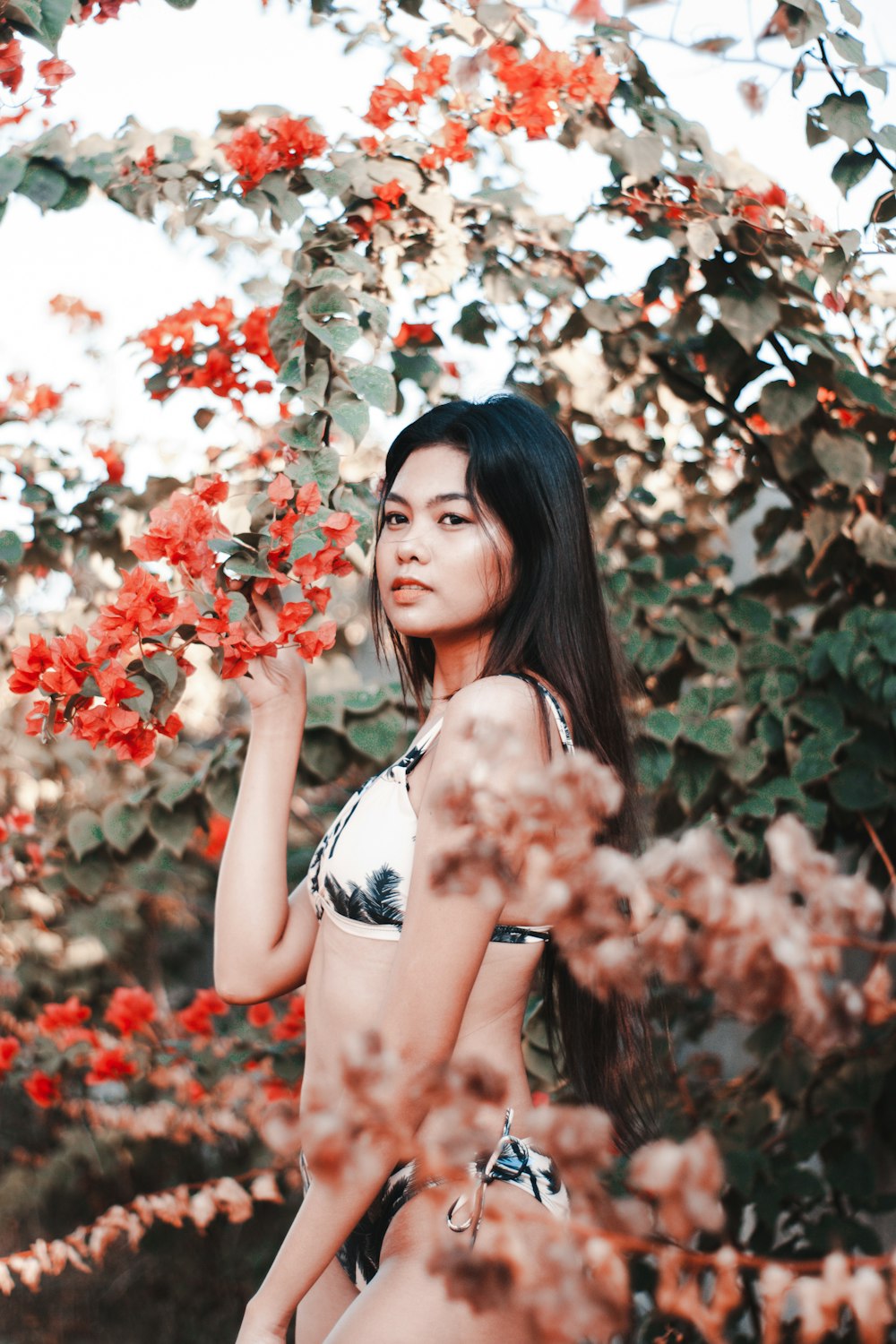 woman under orange flowers in bikini