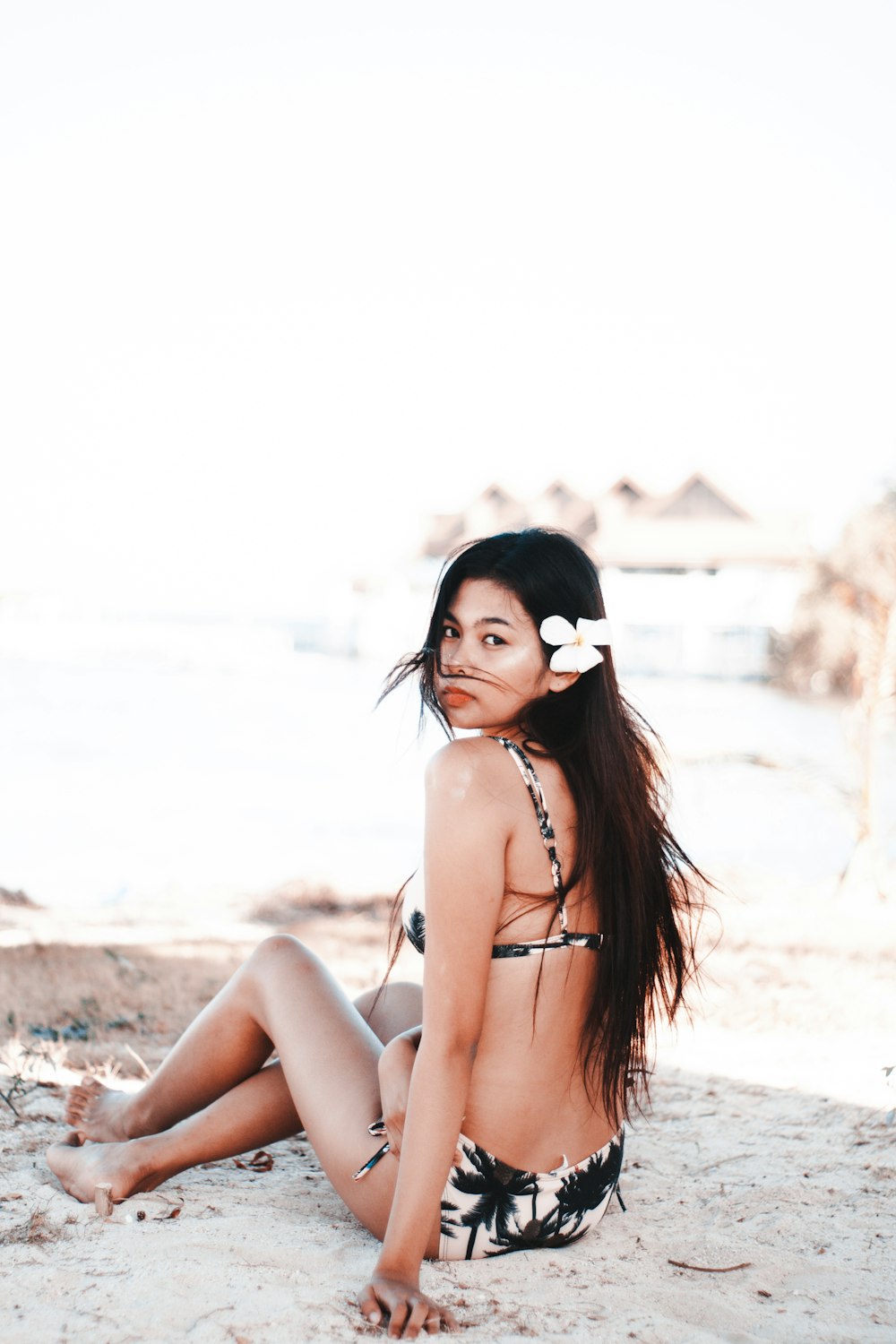 woman in white and black bikini sitting on sand