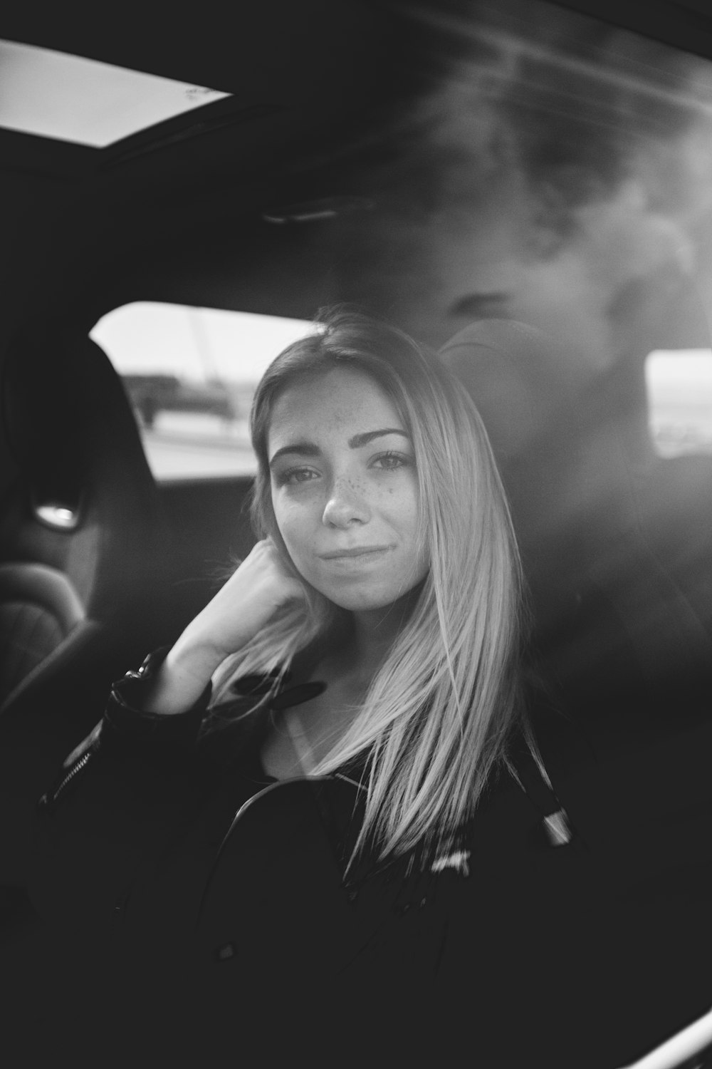 woman in jacket sitting on car