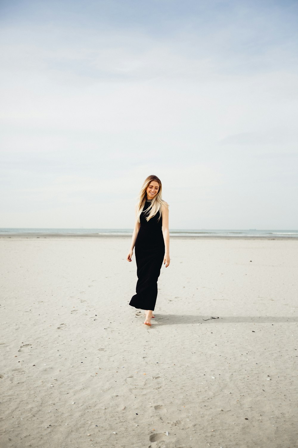 woman wearing black dress standing on the ocean