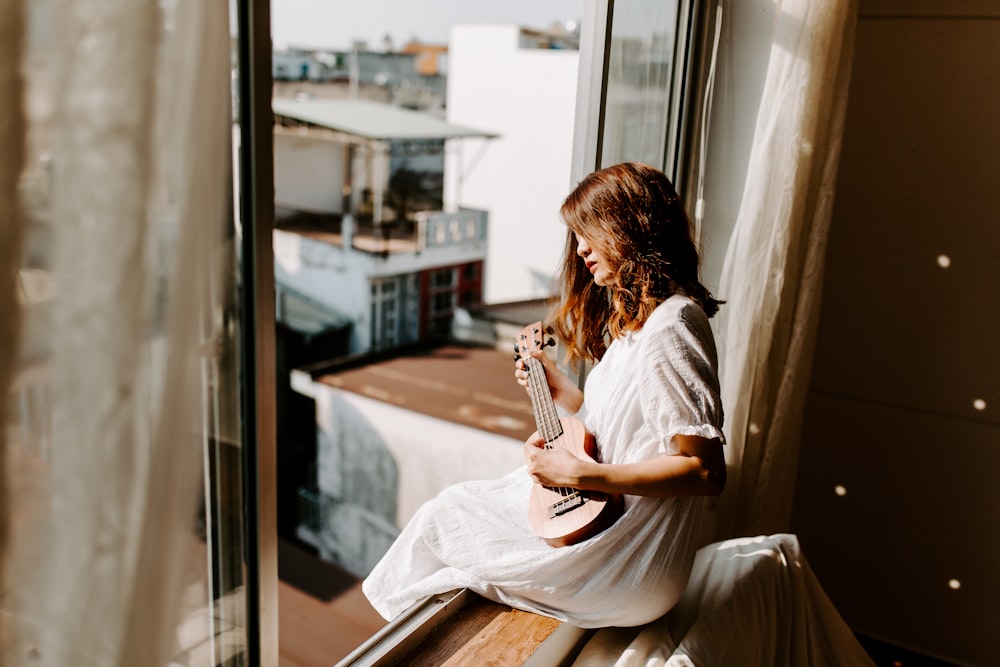 woman sitting on window inside room,