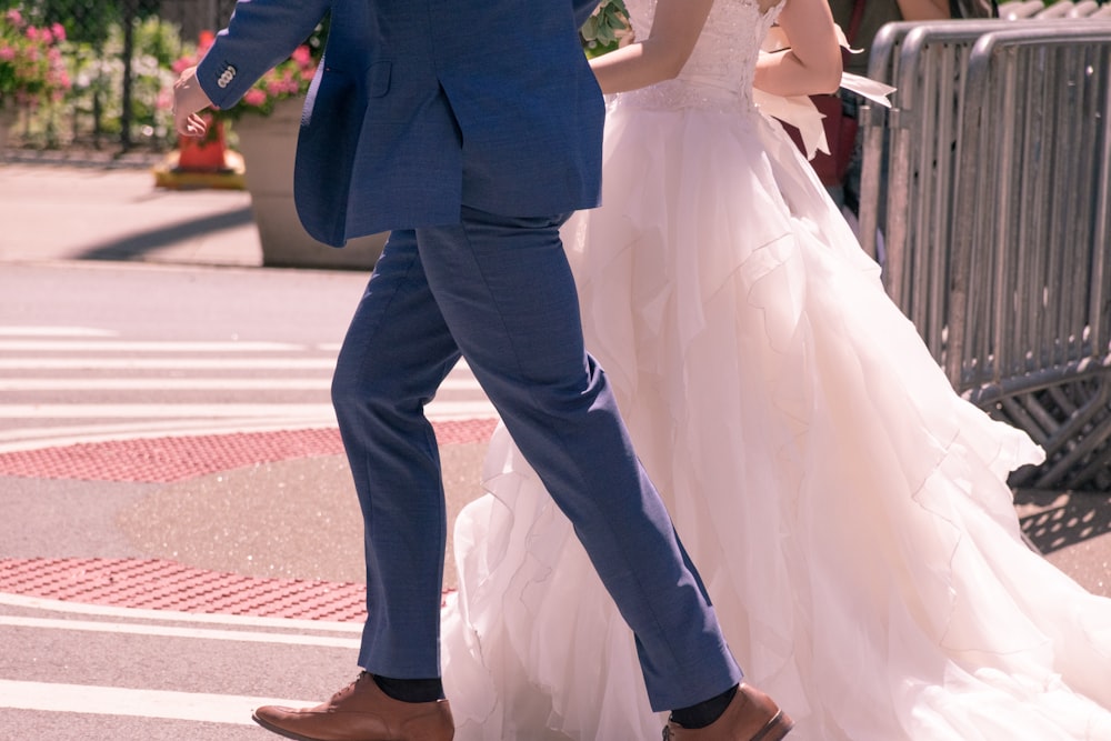 two people wearing wedding dresses walking near metal frames