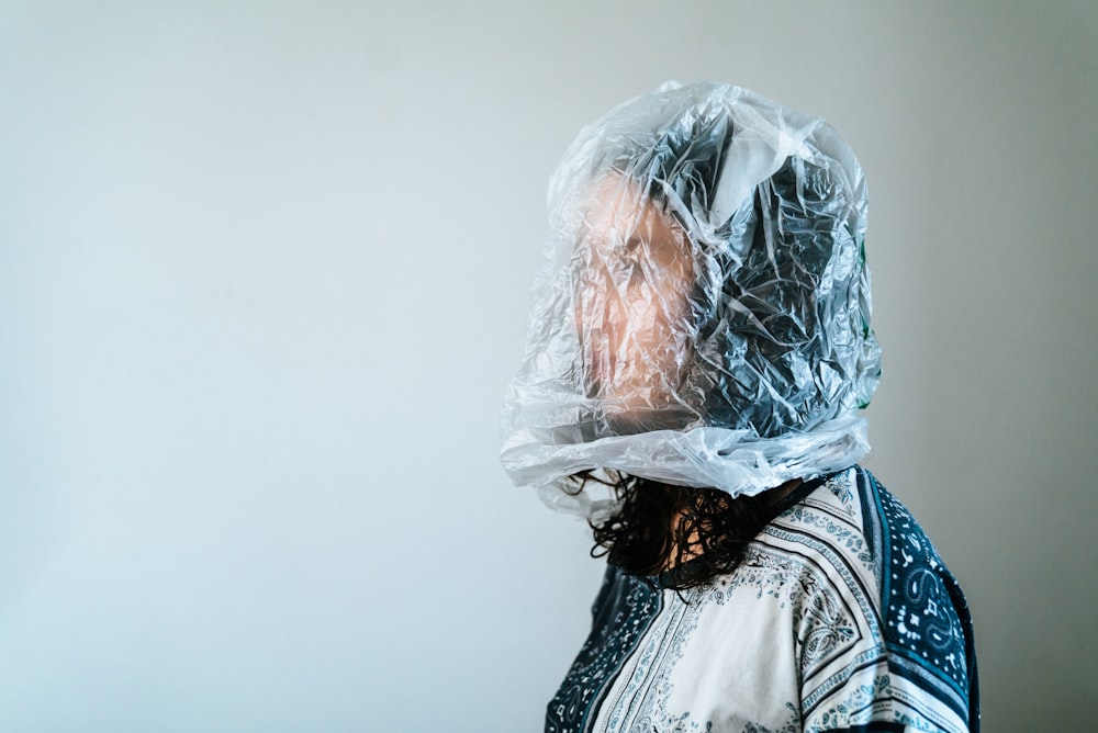 woman in white and blue floral shirt with clear plastic bag on face
