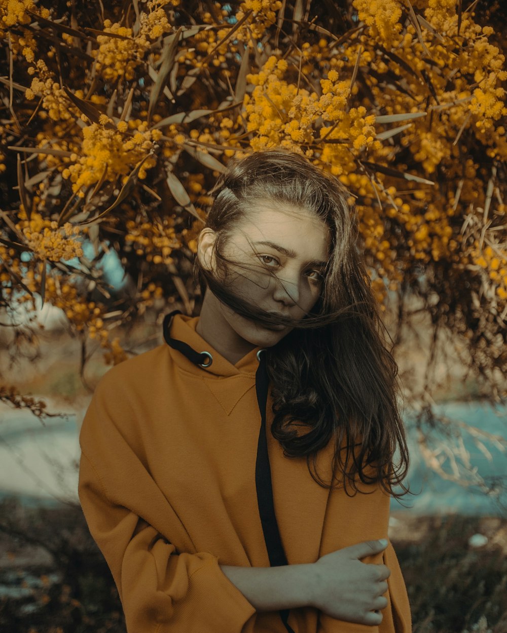 a woman in a brown coat standing in front of a tree