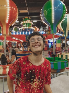 Smiling family enjoying a birthday party with vibrant amusement park rides in the background.